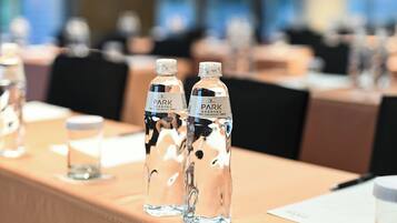 Una mesa de conferencias con botellas de agua que dicen "PARK" y un vaso de agua.
