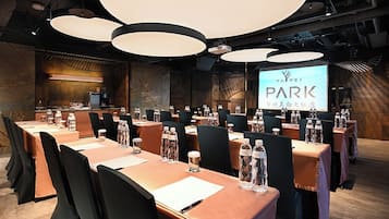 Un salón de conferencias con mesas, sillas y una pantalla grande que muestra la marca 'TAIPEI PARK'.