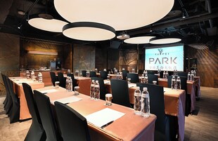 Un salón de conferencias con mesas, sillas y una pantalla grande que muestra la marca 'TAIPEI PARK'.