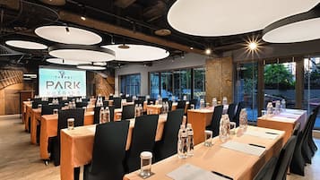 Un salón de conferencias con varias mesas, sillas y una pantalla grande mostrando 'Taipei Park'.
