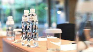 Een hotel receptie met een houten balie waarop waterflessen en glazen staan.