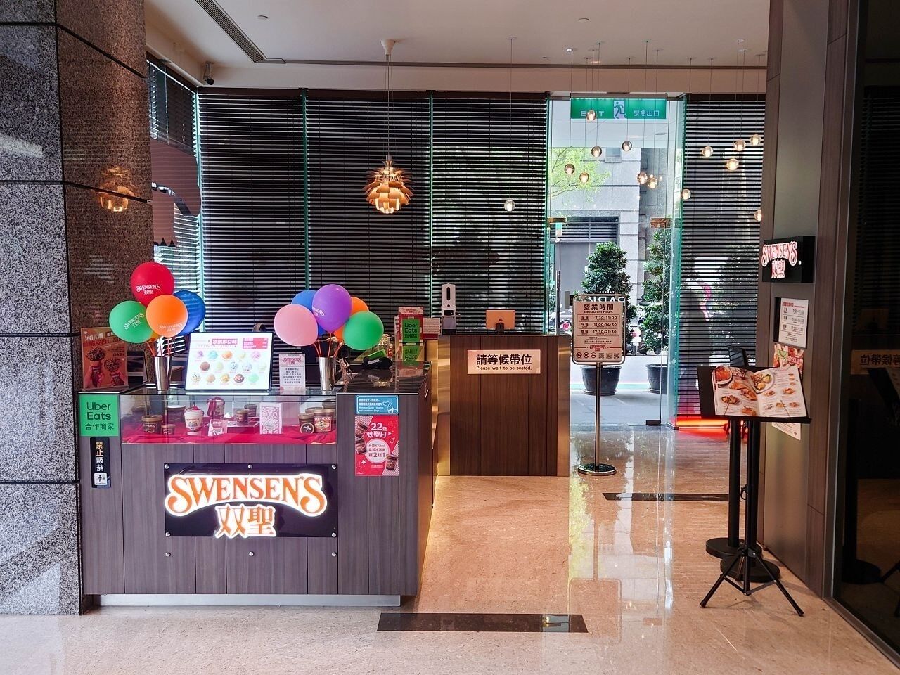 Restaurante SWENSENS com balcão, balões e suporte para cardápio.