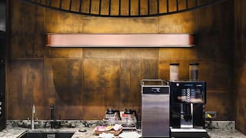 Una cocina moderna con una cafetera espresso de acero inoxidable, un molinillo de café y un fregadero.