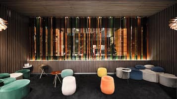 Een modern interieur met een zithoek, inclusief kleurrijke poefs en een groot raam met verticale jaloezieën.