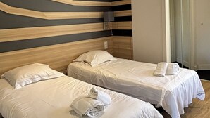 A hotel room with two beds, a modern design with wooden headboards and a dark wall.
