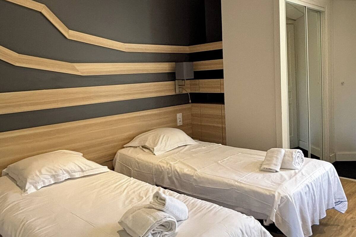 A hotel room with two beds, a modern design with wooden headboards and a dark wall.