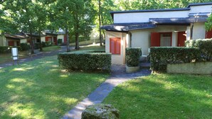 A residential building with a paved pathway leading to the entrance, surrounded by well-maintained hedges and a grassy lawn.