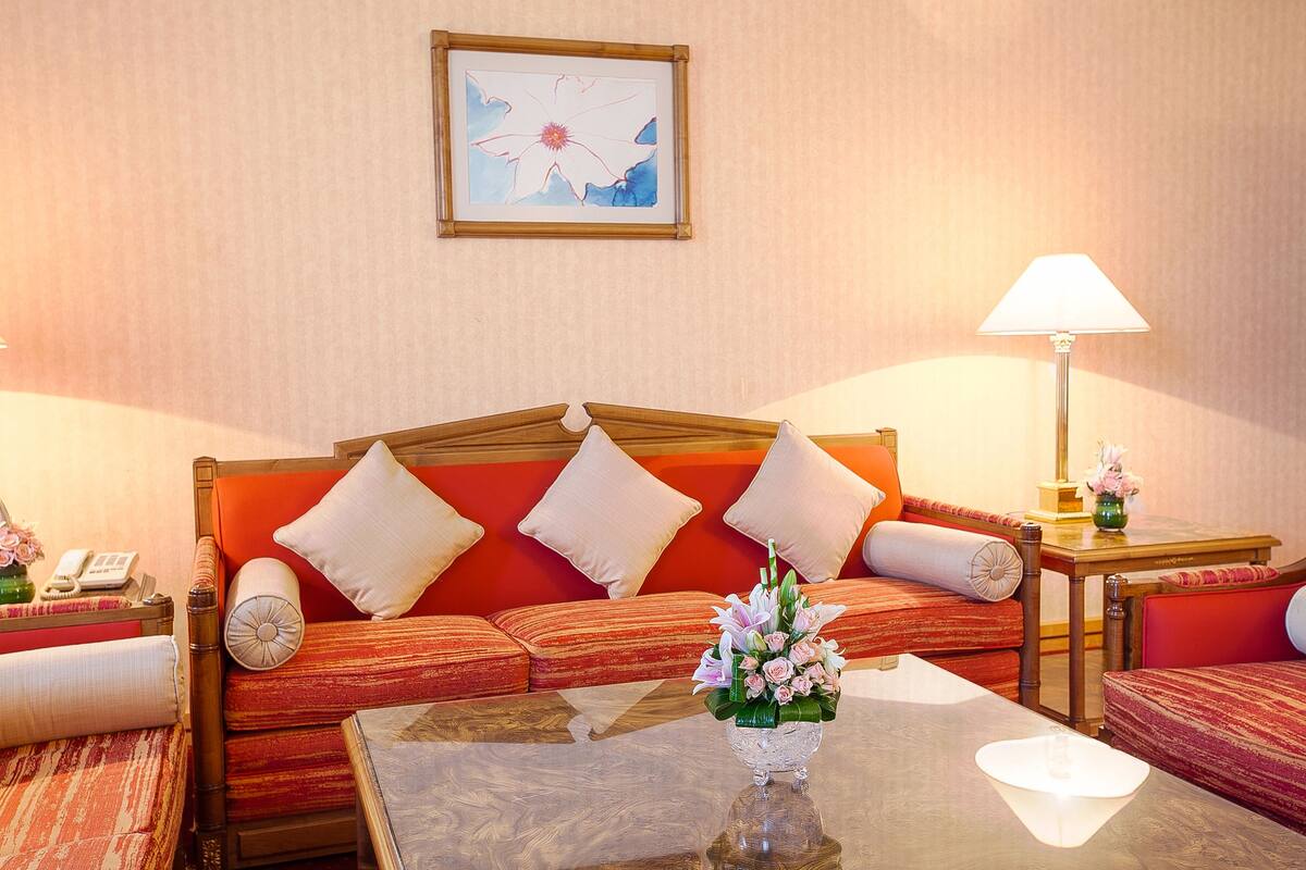 Una habitación de hotel con un conjunto de sofás, una mesa de centro, una lámpara y una obra de arte enmarcada en la pared.
