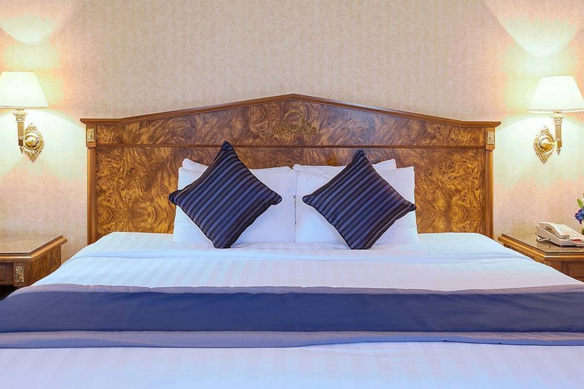 Una habitación de hotel con una cama grande, dos lámparas fijadas a la pared y un teléfono en la mesita de noche.