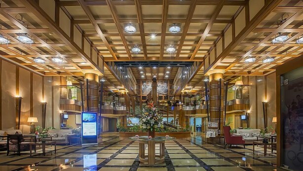 A spacious lobby with a checkered floor, a central floral arrangement, and a modern ceiling design. - Capitol Hotel (Dubai)