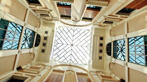 A spacious atrium with high ceilings, large windows, and a geometric patterned skylight. - Capitol Hotel (Dubai)
