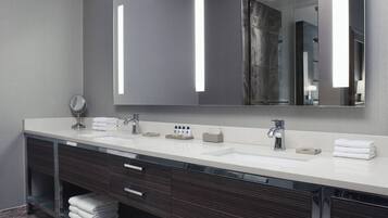 Un baño moderno con un espejo grande, dos lavamanos y un mueble de tocador con cajones.
