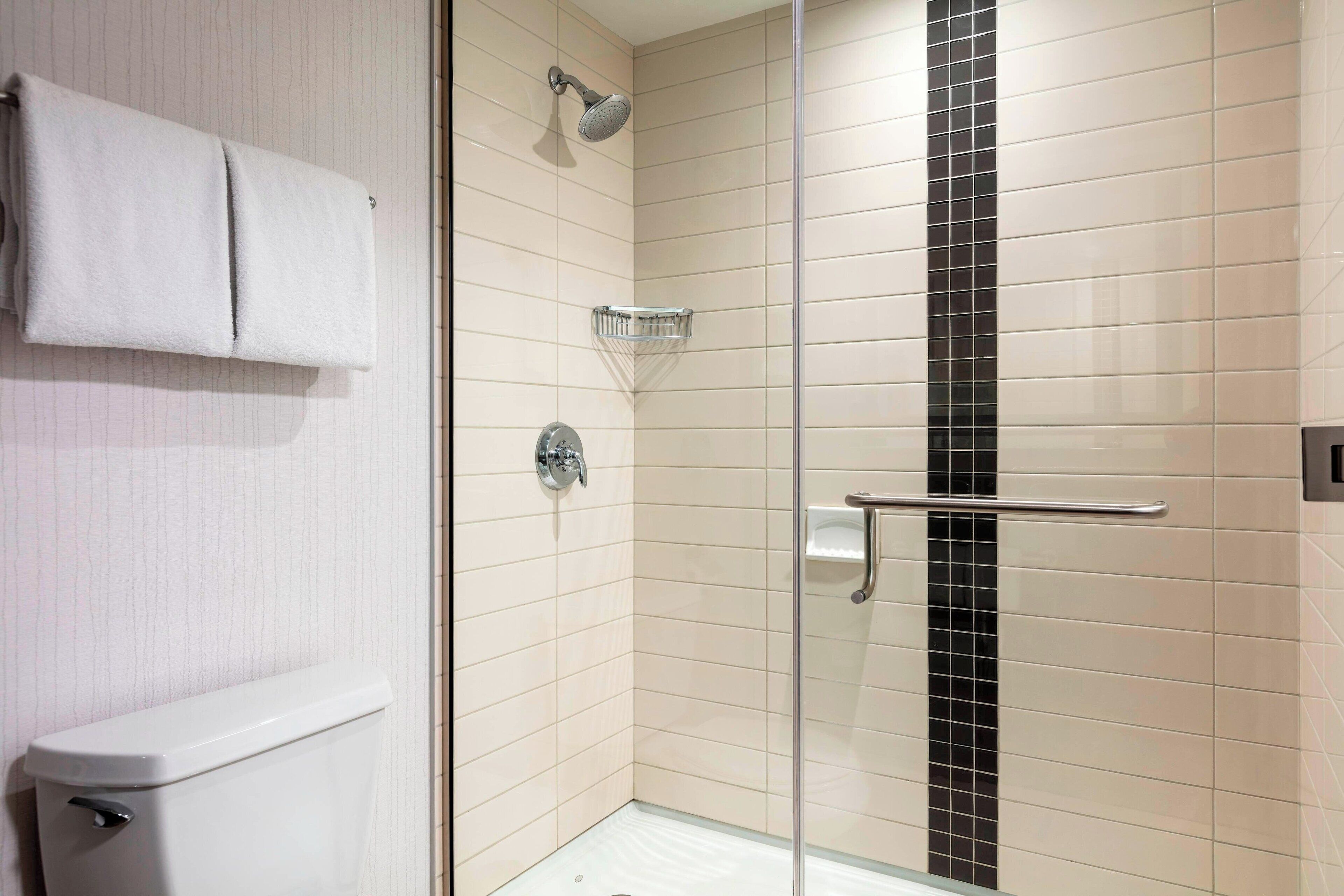 Een moderne badkamer met een douchecabine van glas, een toilet en een handdoekrek.
