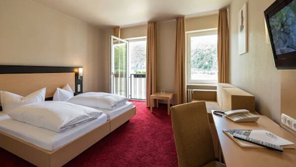 A hotel room with two beds, a desk, a chair, and a television.