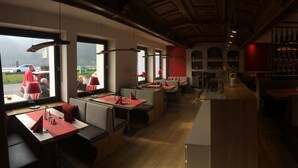 A restaurant with booths and tables, wooden flooring, and a view of the outside.