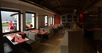 Un restaurante con mesas y cabinas, piso de madera y vistas al exterior.