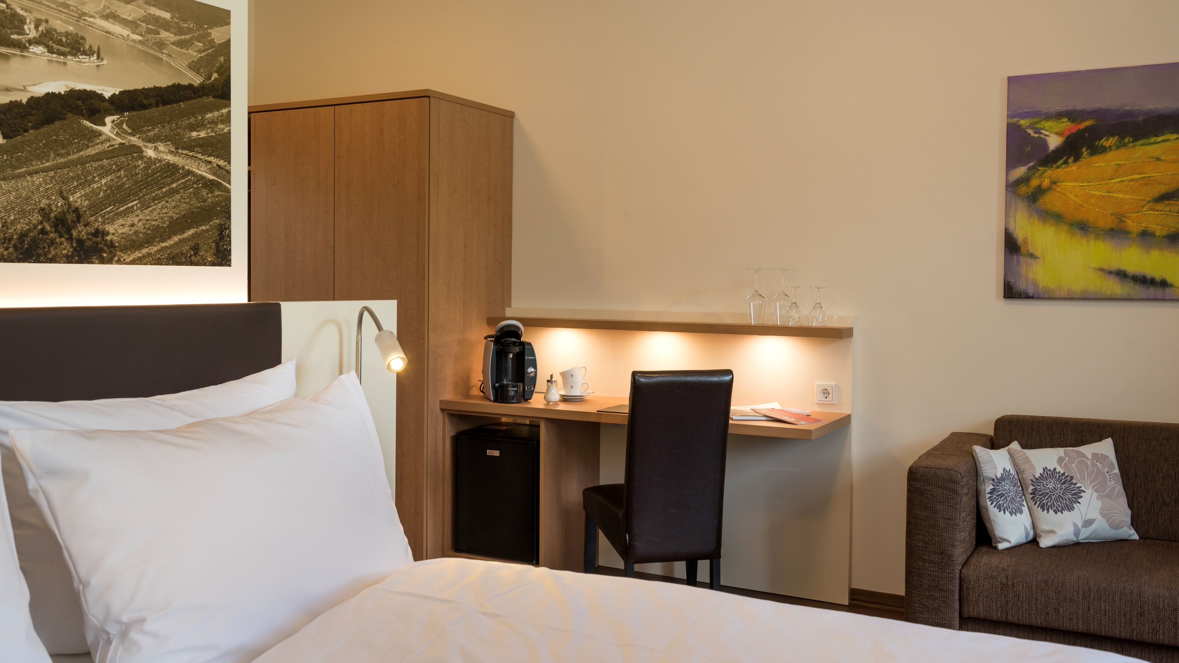 Une chambre d’hôtel comprenant un lit, un bureau avec une machine à café, une chaise et un canapé.