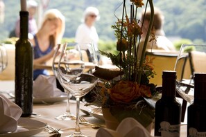 A dining table set with wine glasses, bottles, and a floral centerpiece.