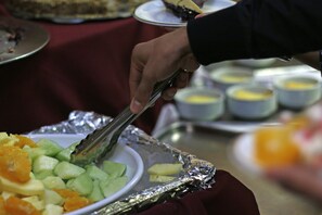 Una mano usando unas pinzas para servir comida de una bandeja.