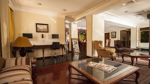 A spacious lobby with a wooden coffee table, striped sofa, and armchairs.