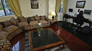 A living room with a sofa, a coffee table, a desk with a computer, and a chair.