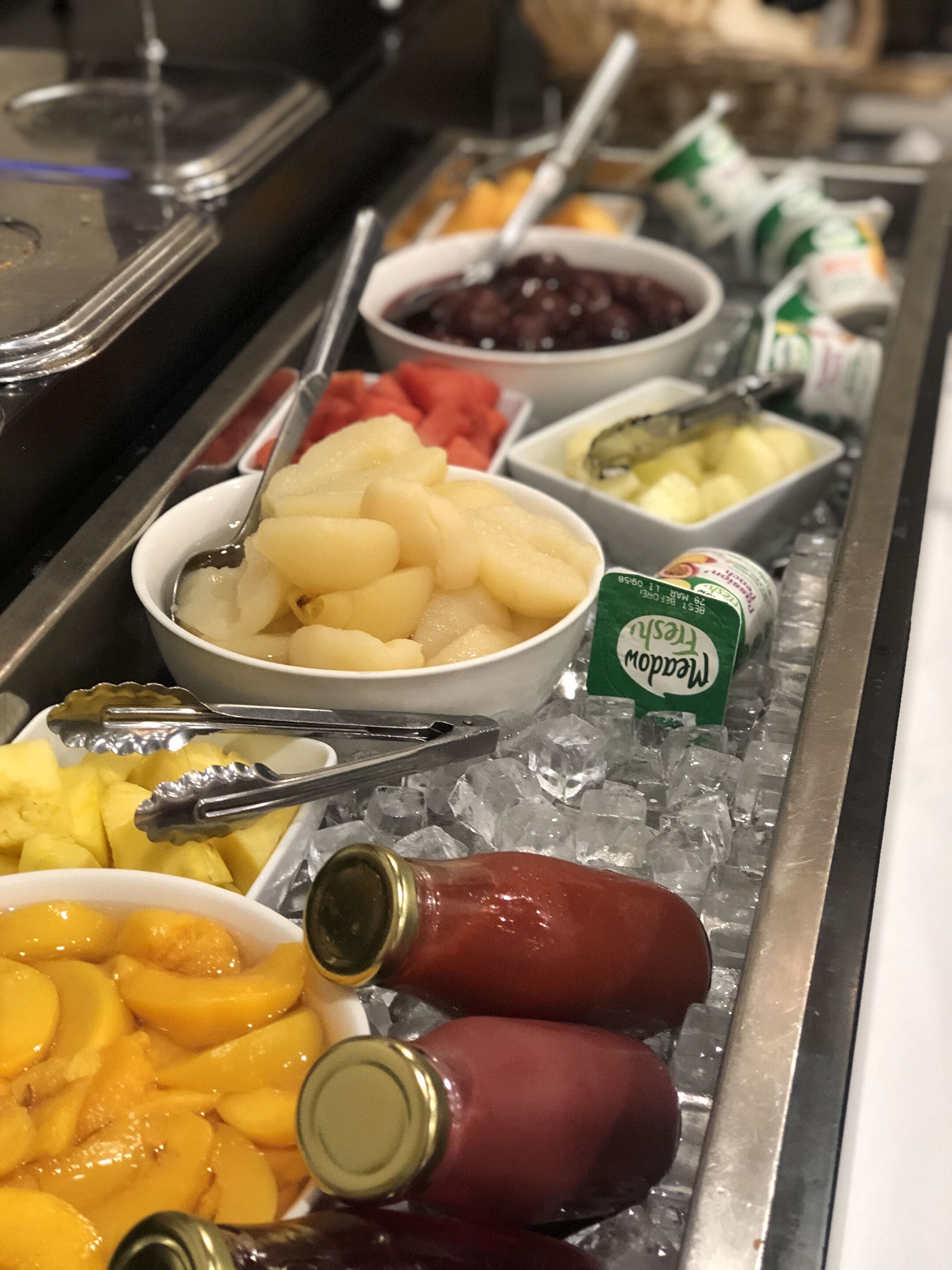 Un bufé con diversos alimentos, entre ellos frutas, verduras y salsas.