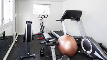 A gym with a treadmill, stationary bike, weights, and exercise balls.