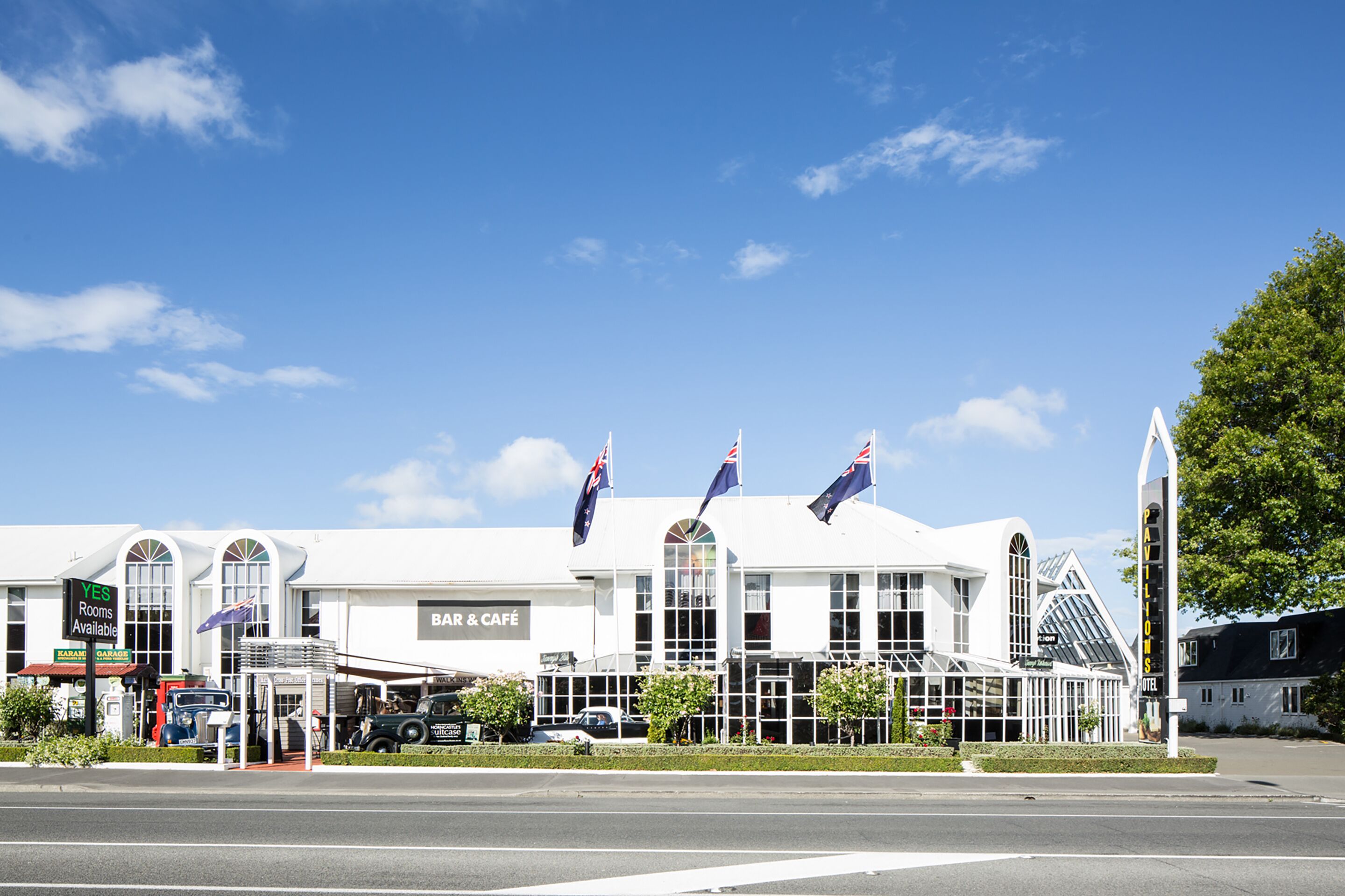 A hotel with a bar and cafe, multiple flags, and a modern architectural design.