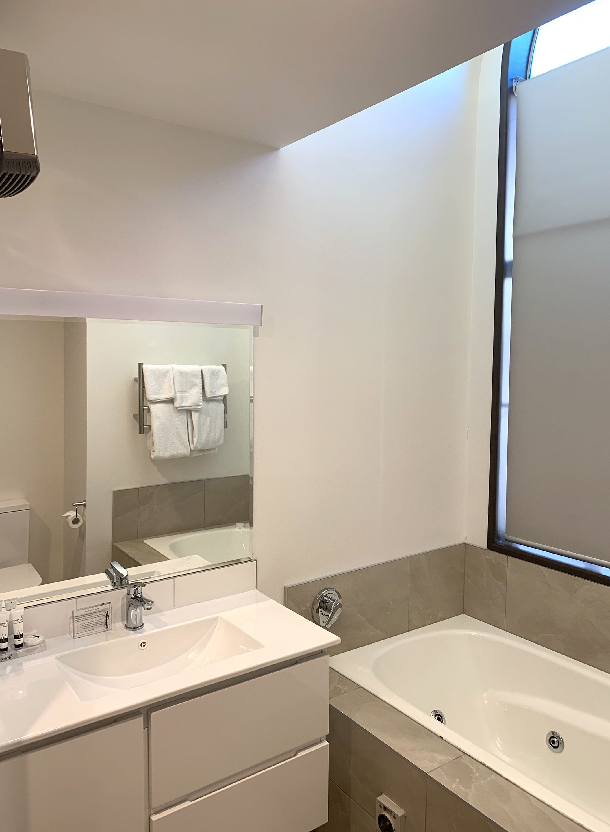 Un baño moderno con dos lavamanos, un espejo grande y una bañera.