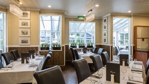 En restaurang med flera bord, stolar och en grön utrymningsskylt.