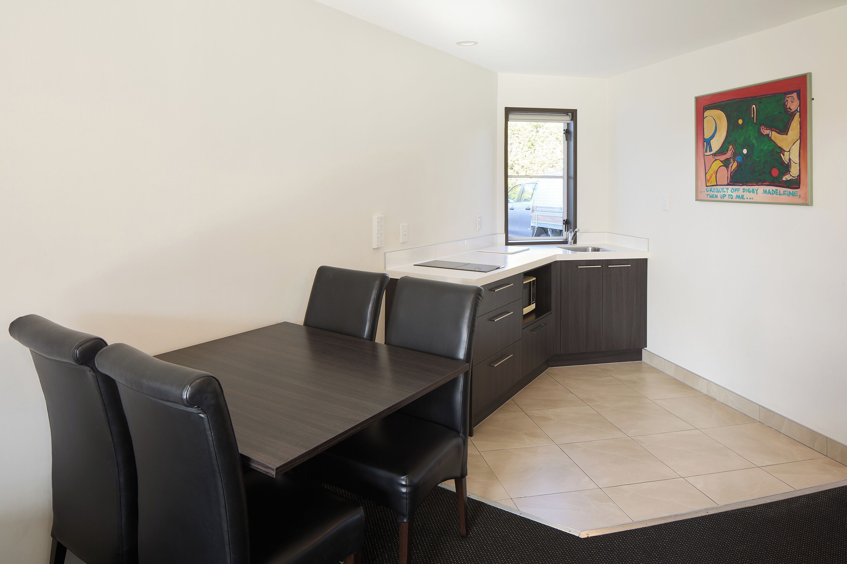 A modern kitchen with a dining area, a window, and a kitchen counter.