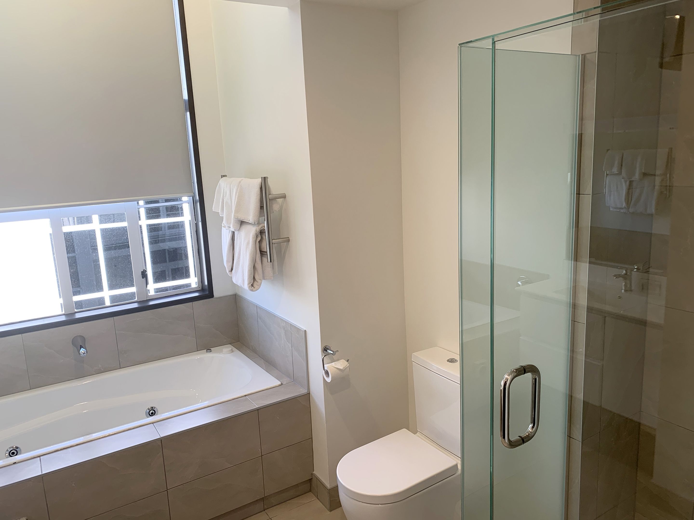 Un baño moderno con ducha acristalada, una bañera blanca y un inodoro.