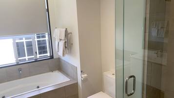 Un baño moderno con ducha acristalada, una bañera blanca y un inodoro.