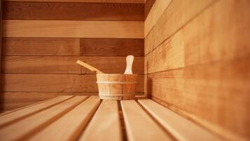 Een houten sauna met banken en een houten emmer met een houten hamer.