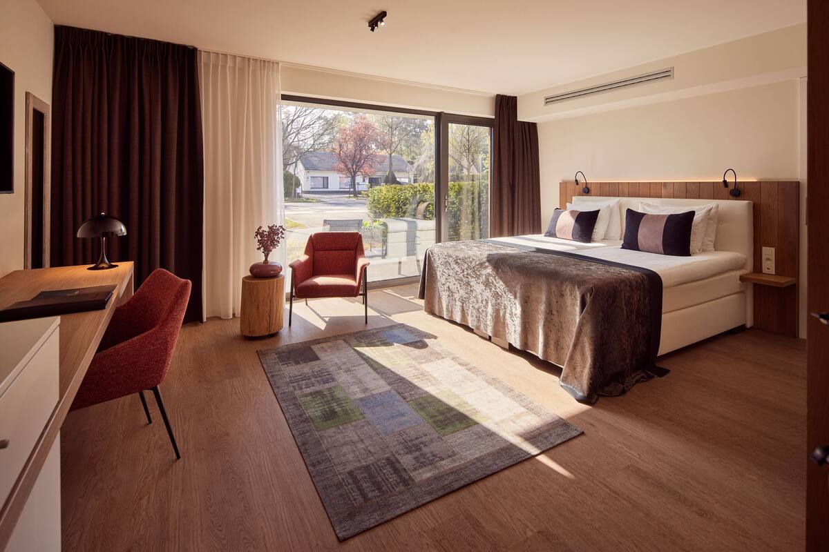 Une chambre d’hôtel avec un lit, un bureau, une chaise et une vue par la fenêtre.