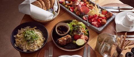 A dining table with various dishes, including pasta, salad, and a charcuterie board.