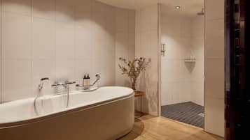 Een moderne badkamer met een vrijstaand bad, een douchegedeelte en een houten vloer.