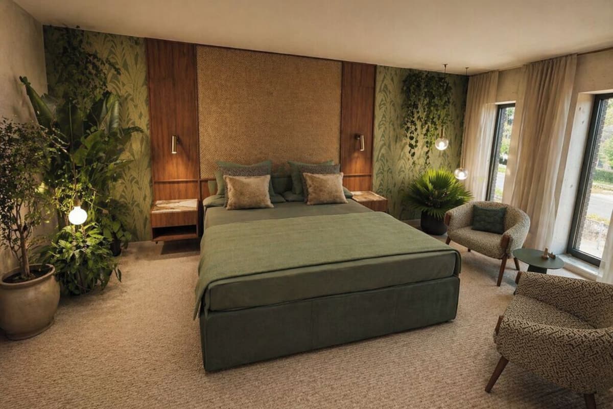 Une chambre à coucher moderne avec un grand lit, un coin salon avec un fauteuil et une plante en pot.