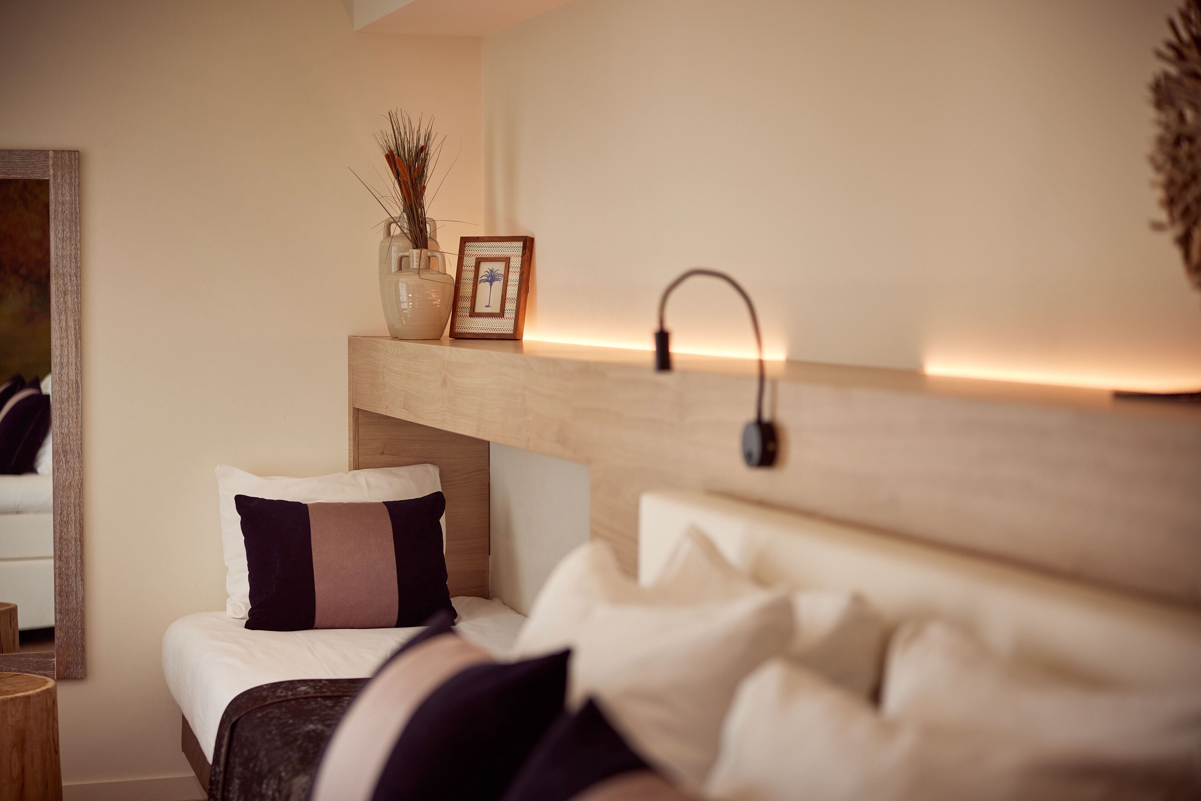 Une chambre à coucher bien rangée, avec un lit, une table de chevet et une étagère ornée d’objets décoratifs.