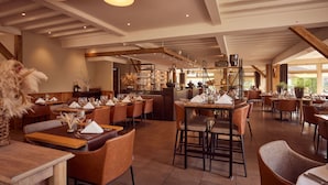 A spacious restaurant with high ceilings, exposed beams, and a variety of seating arrangements including tables and booths. - Van Der Valk Hotel Dennenhof (Brasschaat)