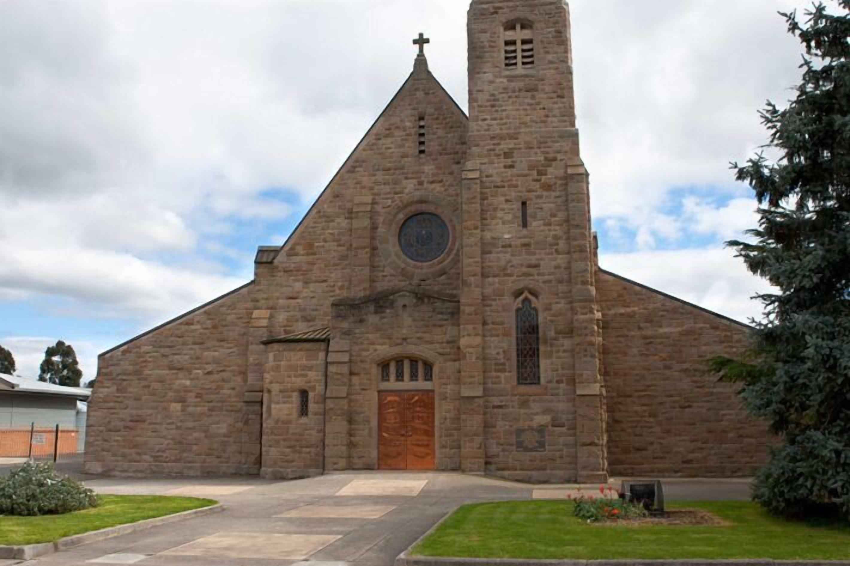 A stone church with a tall tower, a wooden door, and a circular window.