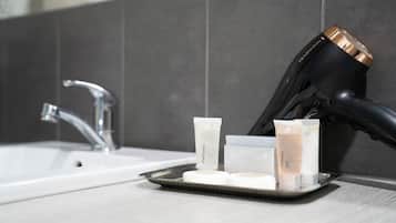 A bathroom with a white sink, a hairdryer, and three toiletries on a tray.