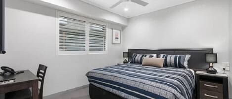 A bedroom with a bed, bedside tables, a desk, and a chair.