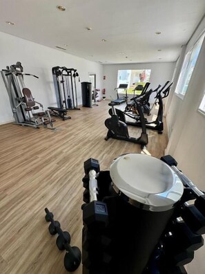 Une salle de sport équipée de machines de cardio, de matériel de musculation et d’un miroir.