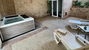 A spa room with a hot tub, a massage table, and a small table with a candle. - Hotel Isla de Cabrera (Ses Salines)