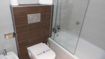 A bathroom with a glass-enclosed shower, a white toilet with a disinfection sign, a bidet, and a towel rack.