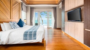 Un dormitorio amplio con una cama grande, paneles de madera, un televisor y vista al mar.