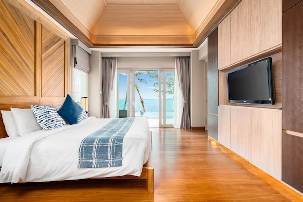 A spacious bedroom with a large bed, wooden paneling, a TV, and a view of the sea. - Fair House Villas & Spa (Koh Samui)