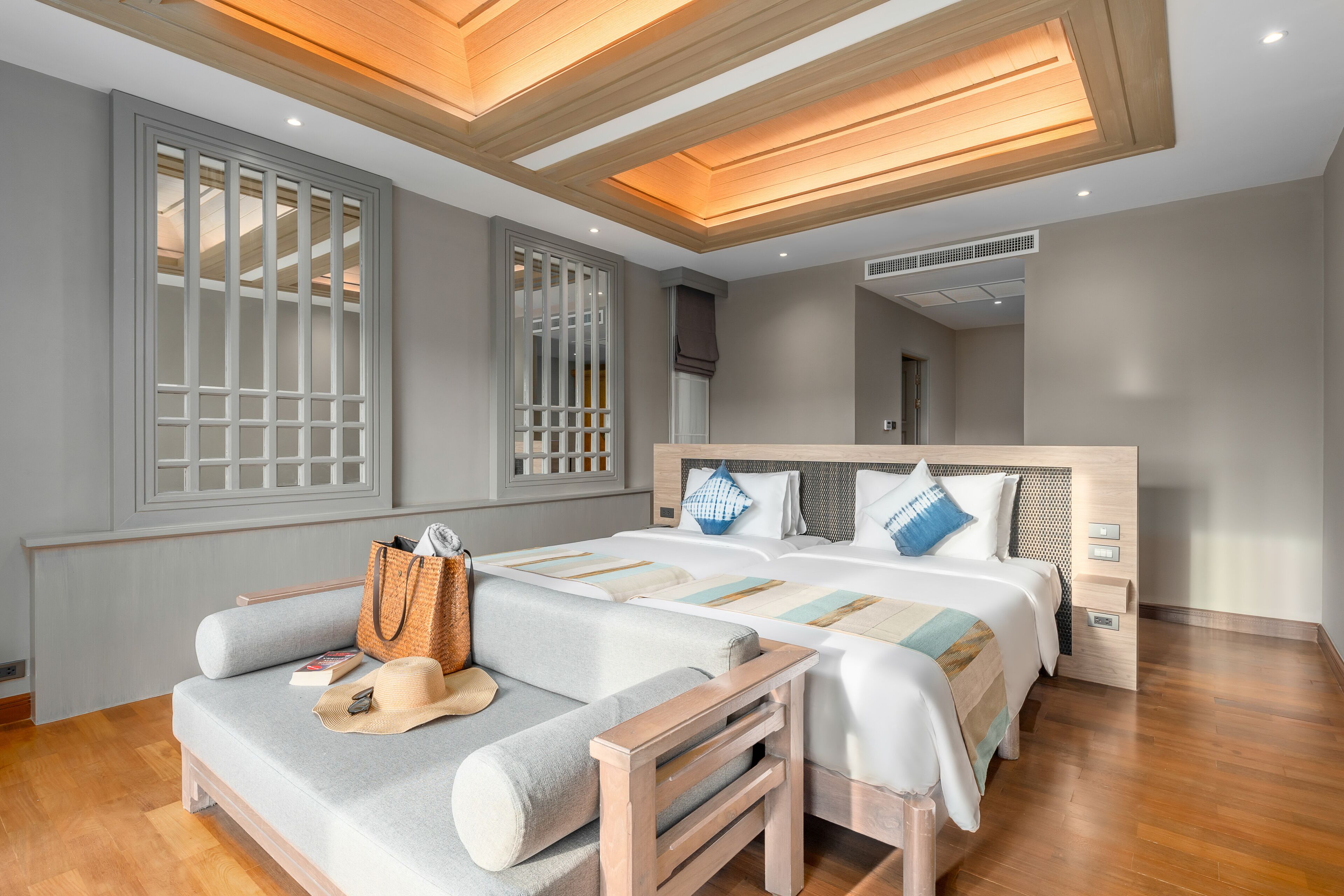 Una habitación de hotel moderna con una cama grande, un sofá y suelo de madera.