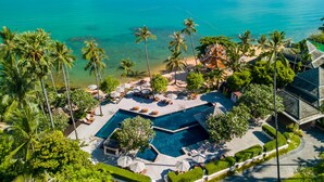 Un resort con piscina, palmeras y vistas al océano.